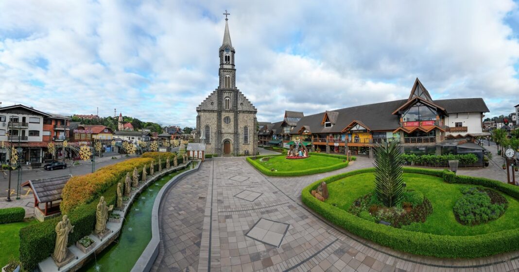 Vista de la arquitectura alpina y calles de Gramado, Brasil, con montañas verdes de fondo.
