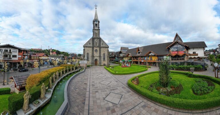 Vista de la arquitectura alpina y calles de Gramado, Brasil, con montañas verdes de fondo.