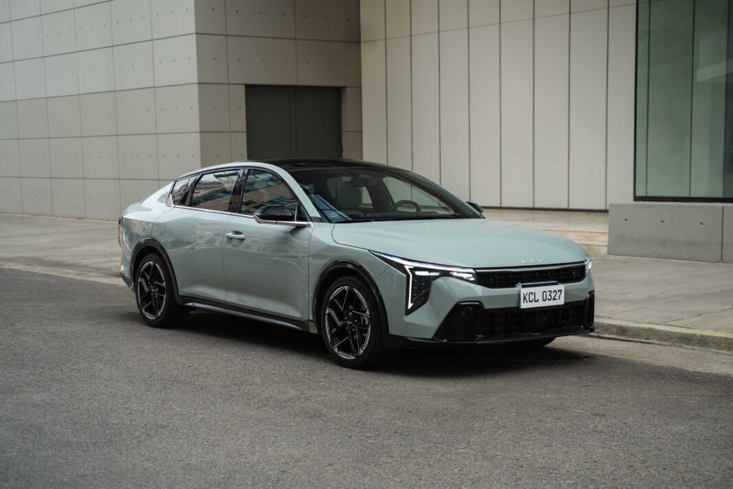 Vista frontal del nuevo Kia K4, sedán de color gris, en un entorno urbano