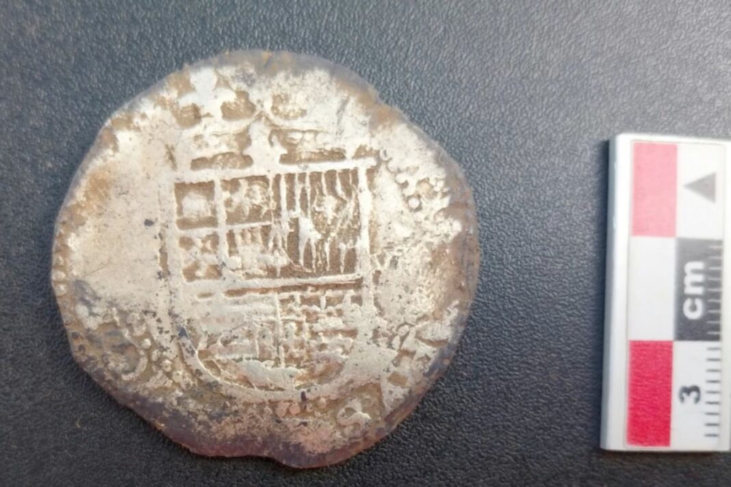 Fotografía de una moneda de plata de ocho reales encontrada en excavaciones arqueológicas.