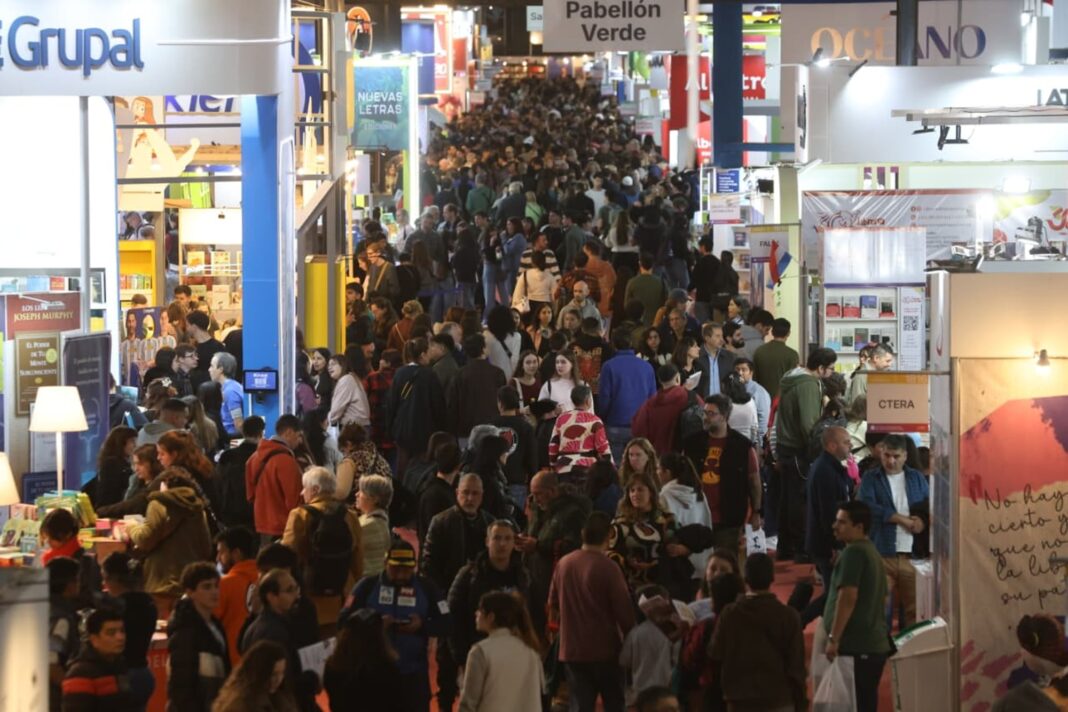 Personas haciendo fila en la Feria del Libro con libros en mano