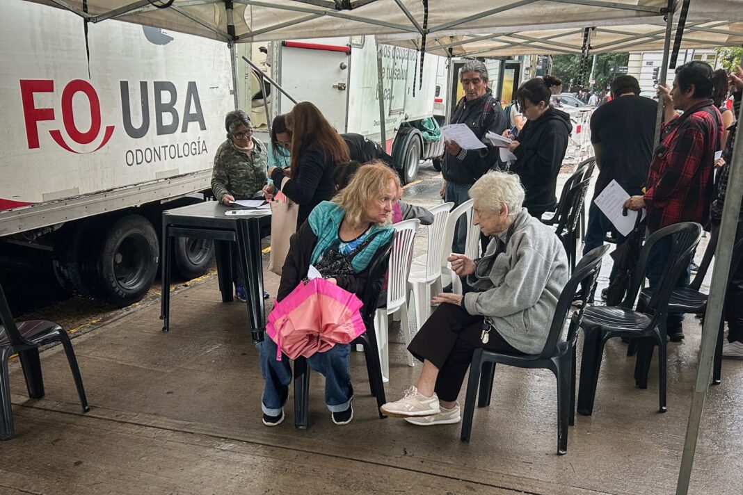 Docente y estudiante de odontología atendiendo a un paciente en un consultorio montado en la calle