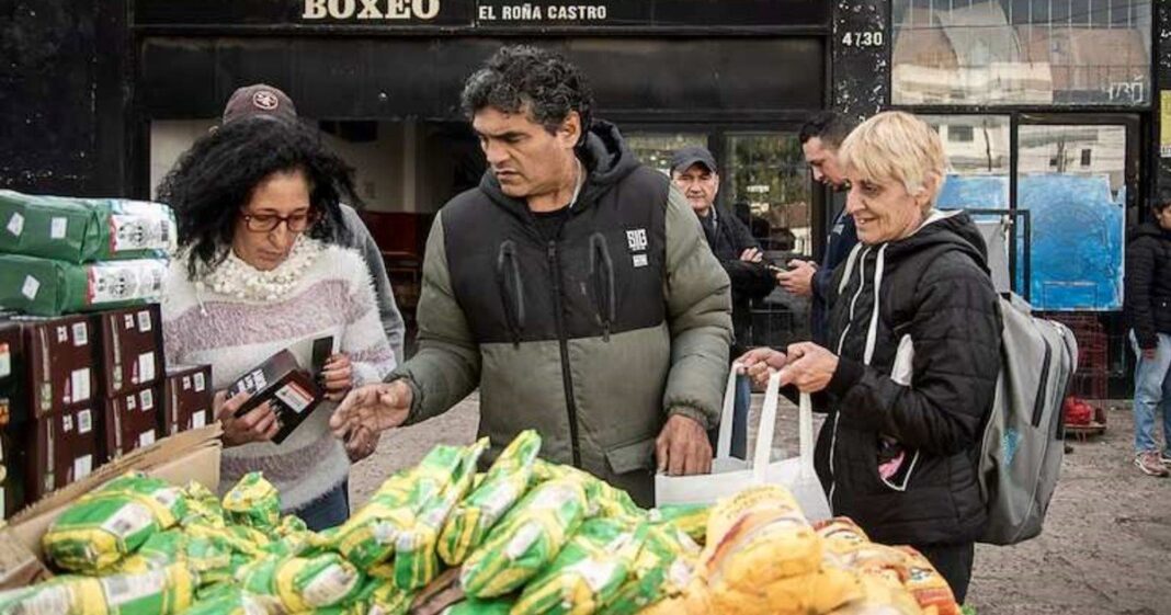 Fila de personas esperando para retirar alimentos frente al gimnasio de Jorge Castro en Temperley