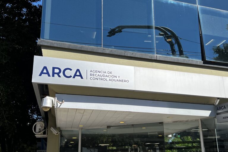 Expedientes judiciales apilados en una mesa, con una lupa y documentos tributarios de fondo