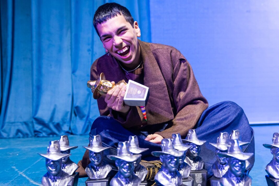 Milo J sosteniendo estatuillas del Premio Gardel en camarines del Teatro Coliseo