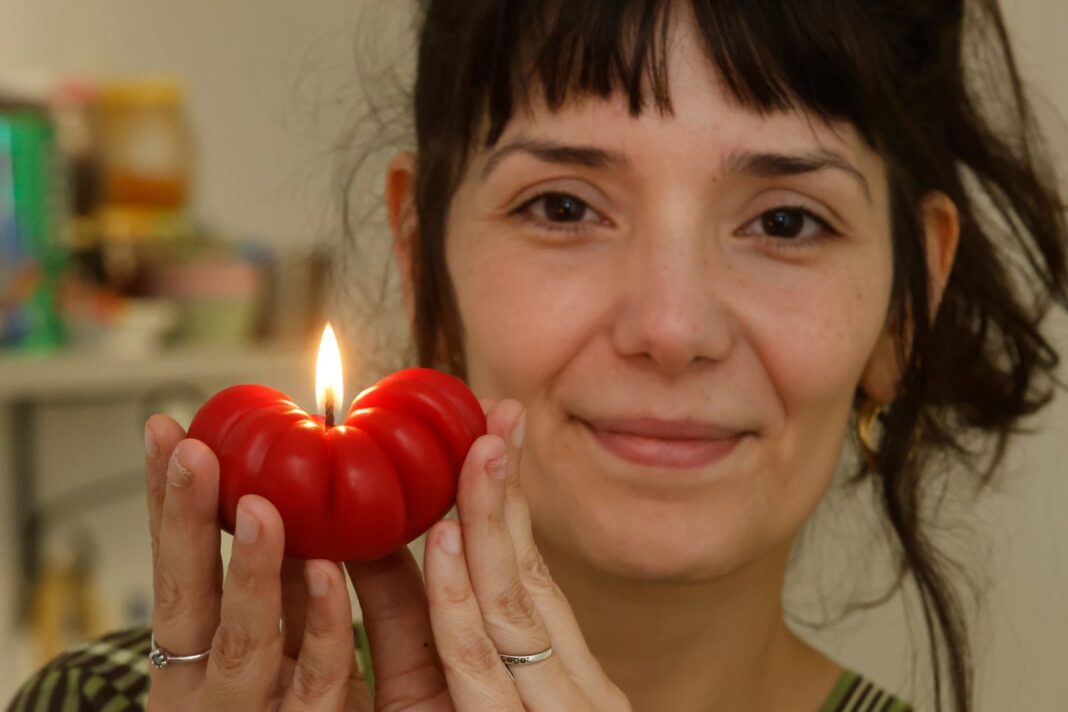 Velas artesanales con forma de cerezas, frutillas y empanadas sobre una mesa