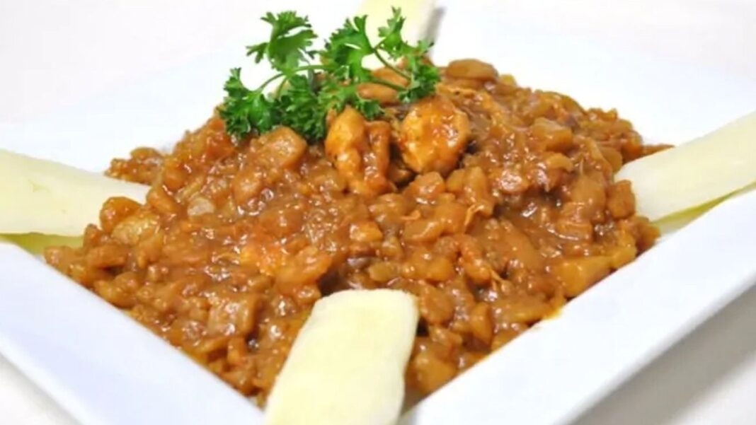 Carapulcra servida en un plato, guiso espeso con papa seca, carne de cerdo y maní tostado