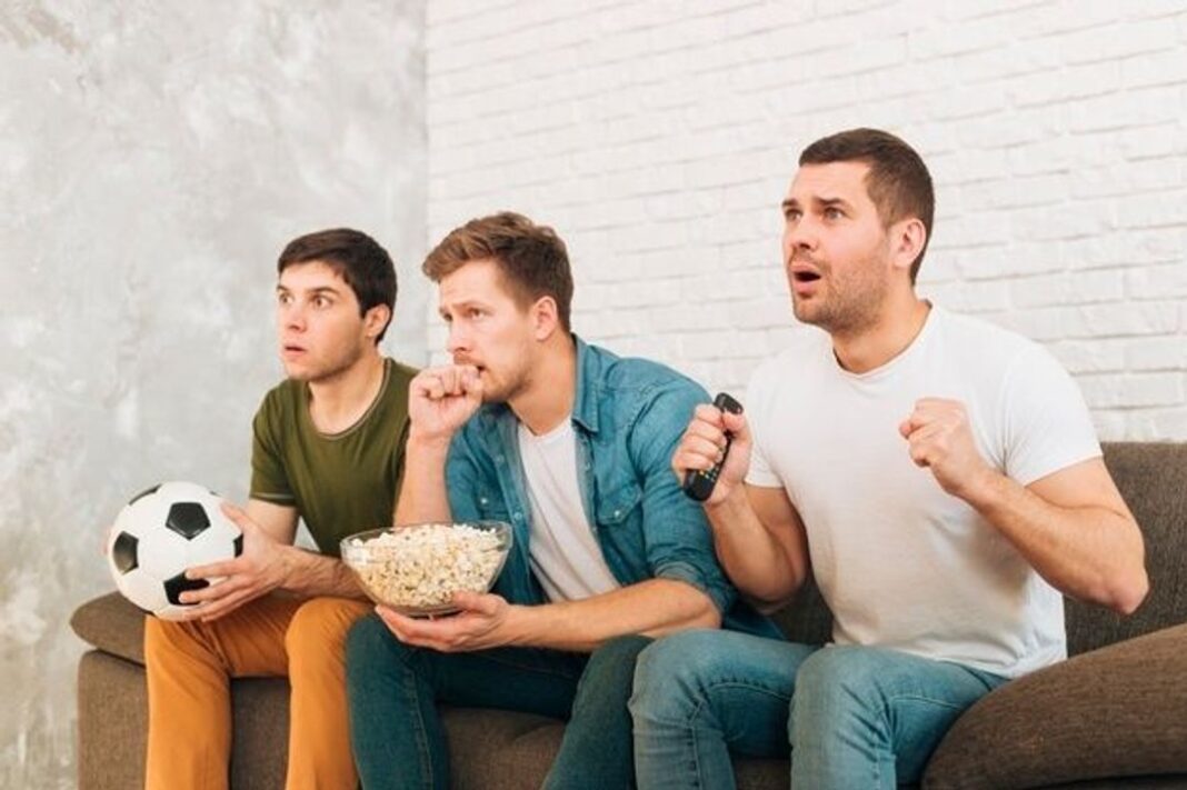Personas viendo un partido de fútbol con una mesa de picada saludable