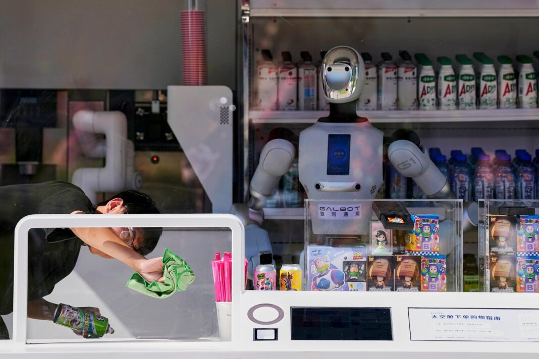 Robot Galbot en una tienda de bebidas de Pekín junto a un joven que limpia el vidrio